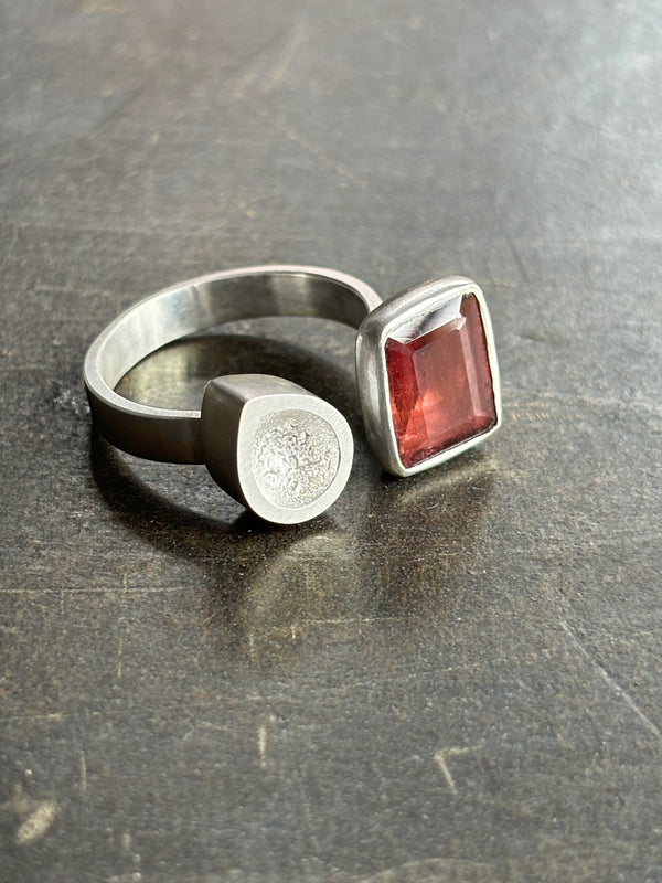 Asymmetric sterling silver ring with rectangular tourmaline on dark leather background