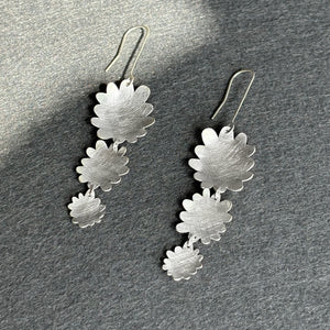 Silver floral earrings on a gray surface