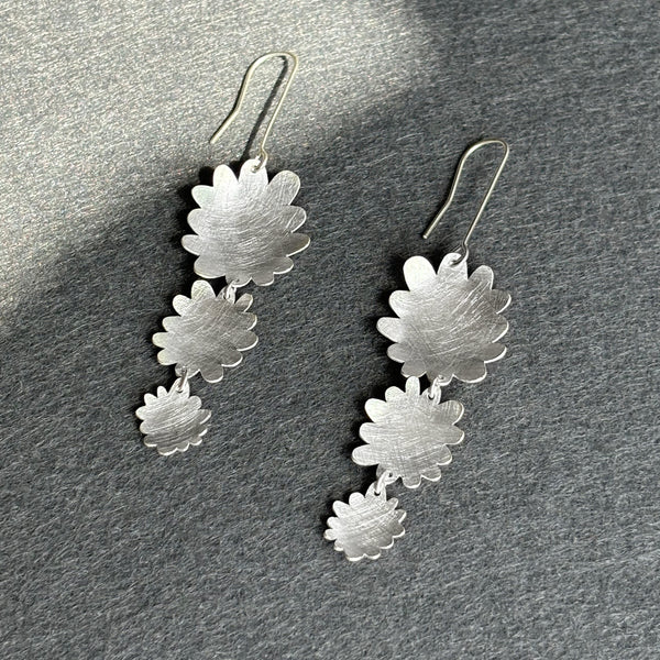 Silver floral earrings on a gray surface