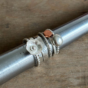 Silver stacking rings on a steel mandrel on a wood background