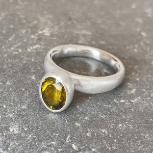 silver ring with green tourmaline stone on a stone prop