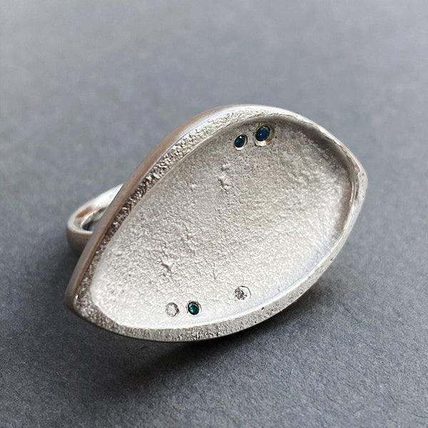 Large chunky sterling silver textured abstract ring with blue and clear diamonds on grey background