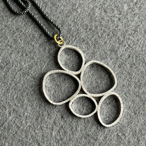 sterling silver lotus outline necklace with oxidised chain and gold connector on grey background
