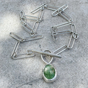 silver handmade chain with t-bar clasp and green aquamarine on a mid grey background
