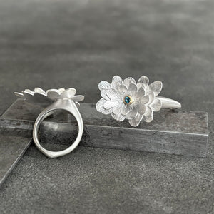 Silver flower gemstone ring on a dark surface