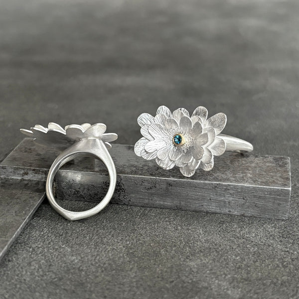 Silver flower gemstone ring on a dark surface