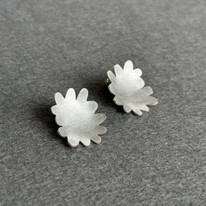 Silver flower-shaped earrings on a gray surface