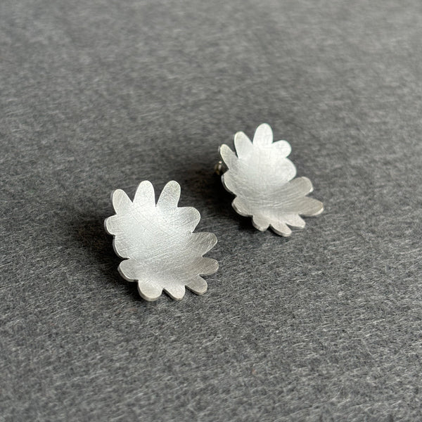 Silver flower-shaped earrings on a gray surface